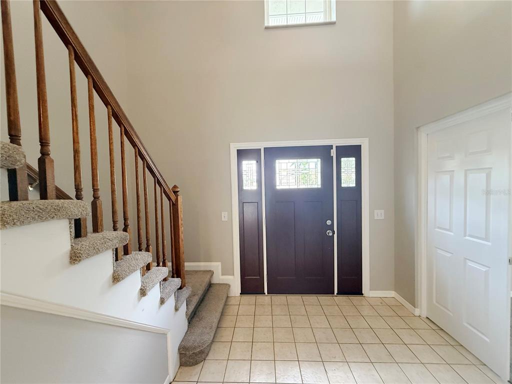 An entryway features a tiled floor, a carpeted staircase with wooden railings, and a dark door — 2609 CRESTFIELD DRIVE, VALRICO, FL