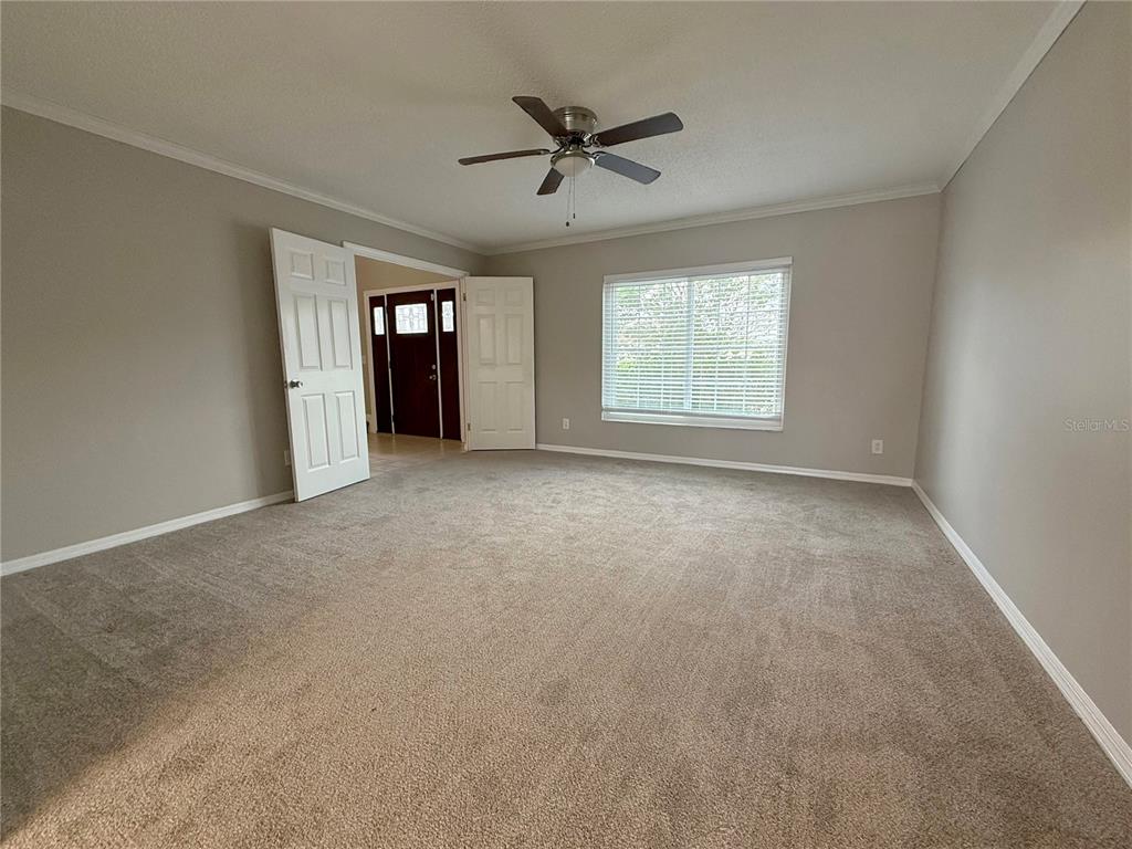 An empty room features beige carpet, light gray walls, a ceiling fan, and a window — 2609 CRESTFIELD DRIVE, VALRICO, FL