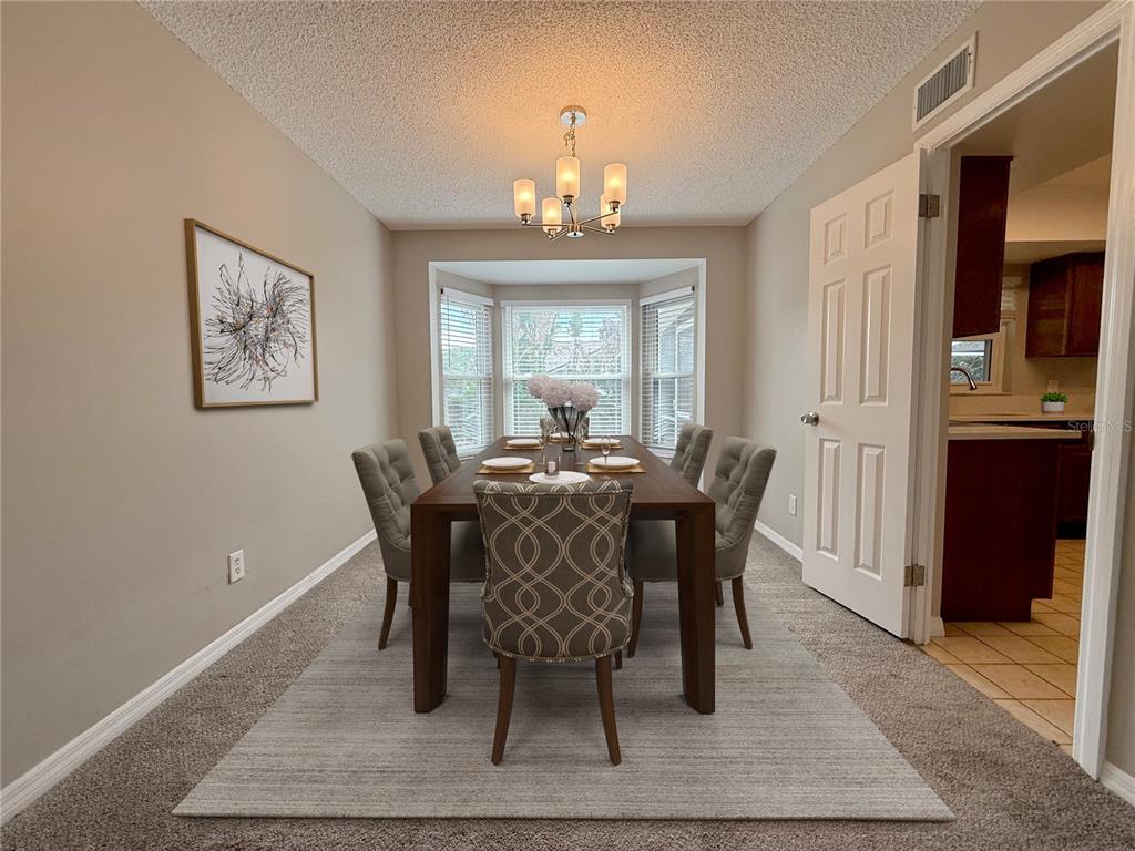 A dining room features a wooden table with six chairs, a chandelier, and carpeted flooring — 2609 CRESTFIELD DRIVE, VALRICO, FL