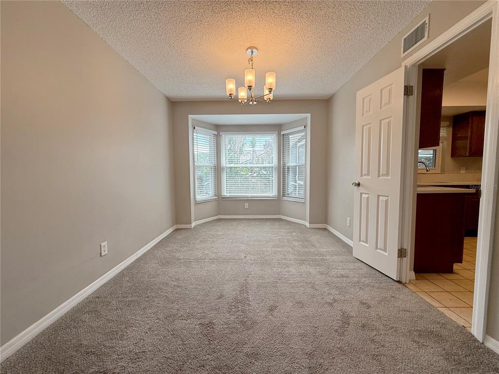 A dining room with beige walls, gray carpeting, a bay window, and a chandelier — 2609 CRESTFIELD DRIVE, VALRICO, FL