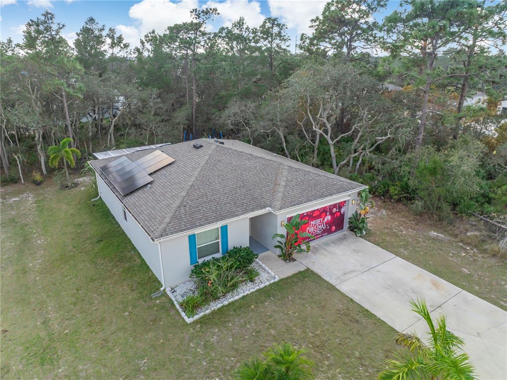 An aerial view shows a single-story house with solar panels and a decorated garage door — 328 HIBISCUS DRIVE, POINCIANA, FL
