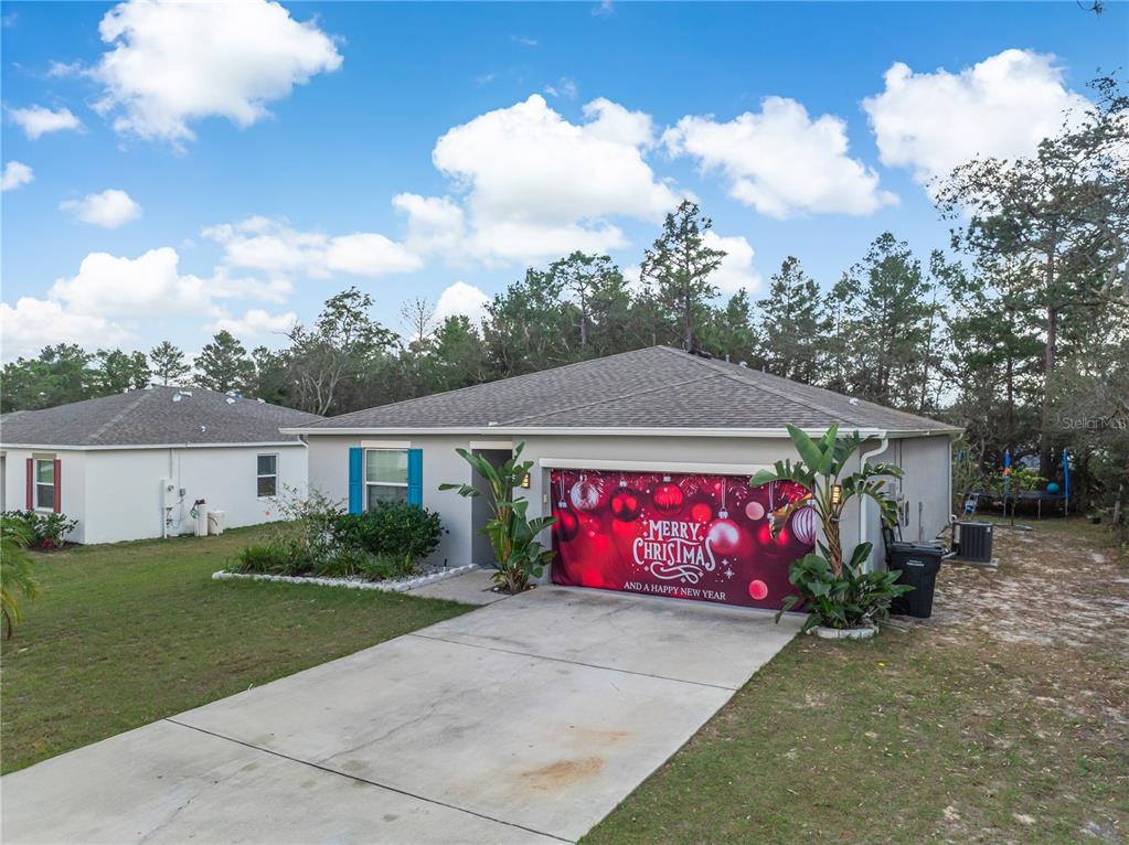 A single-story house with a Christmas-themed garage door cover and a concrete driveway — 328 HIBISCUS DRIVE, POINCIANA, FL