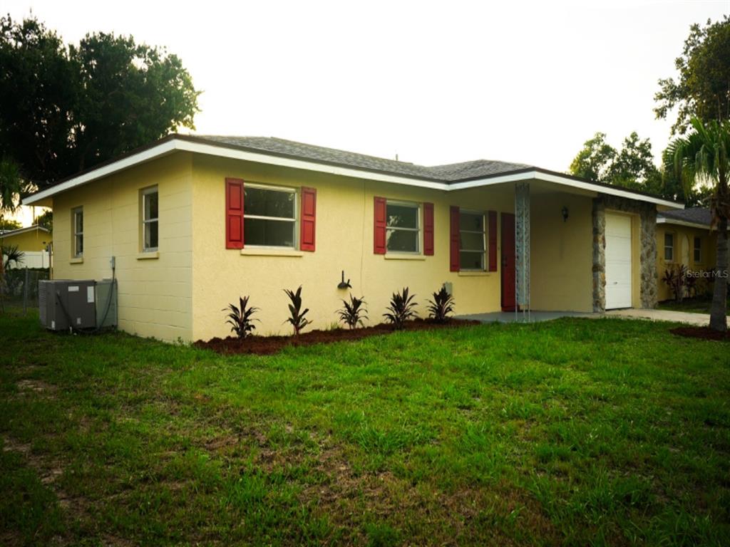 A yellow single-story house with red shutters, a stone-accented garage, and a front lawn — 1051 VENETIAN PARKWAY, VENICE, FL