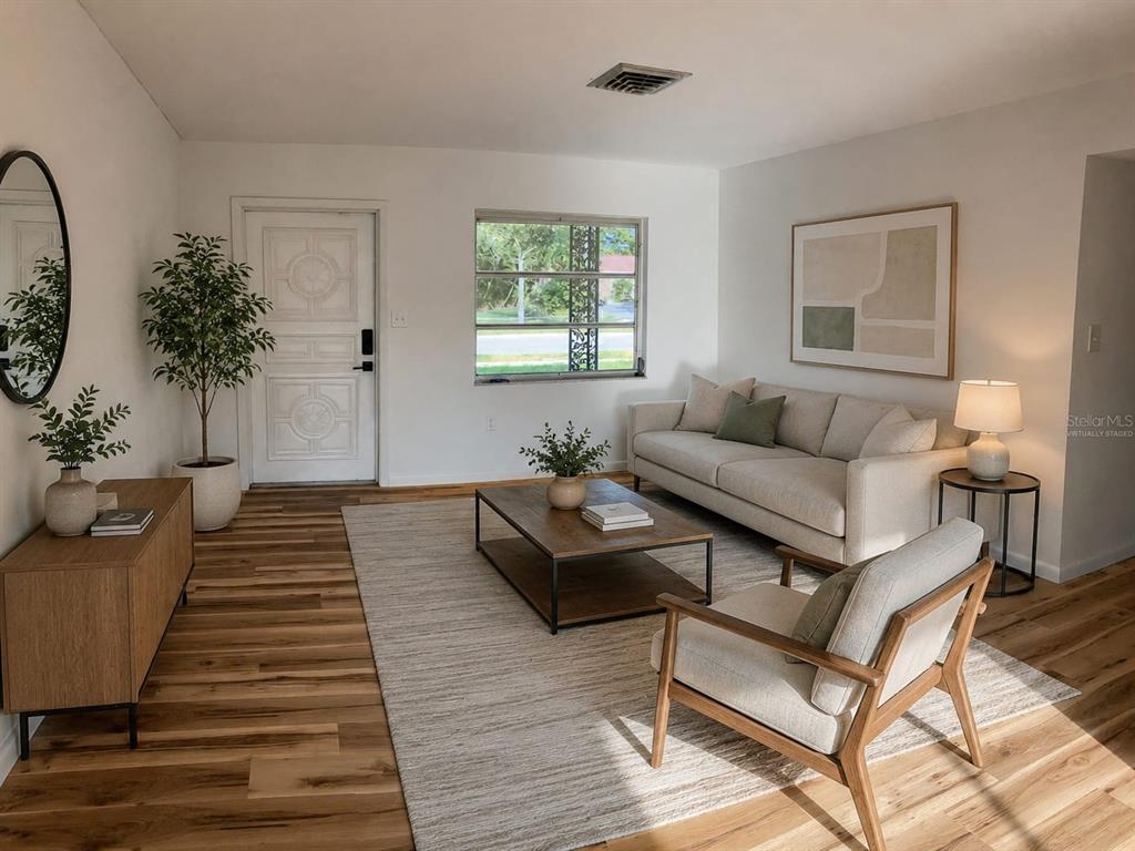A living room features light wood flooring, a beige sofa, an armchair, and a coffee table — 1051 VENETIAN PARKWAY, VENICE, FL