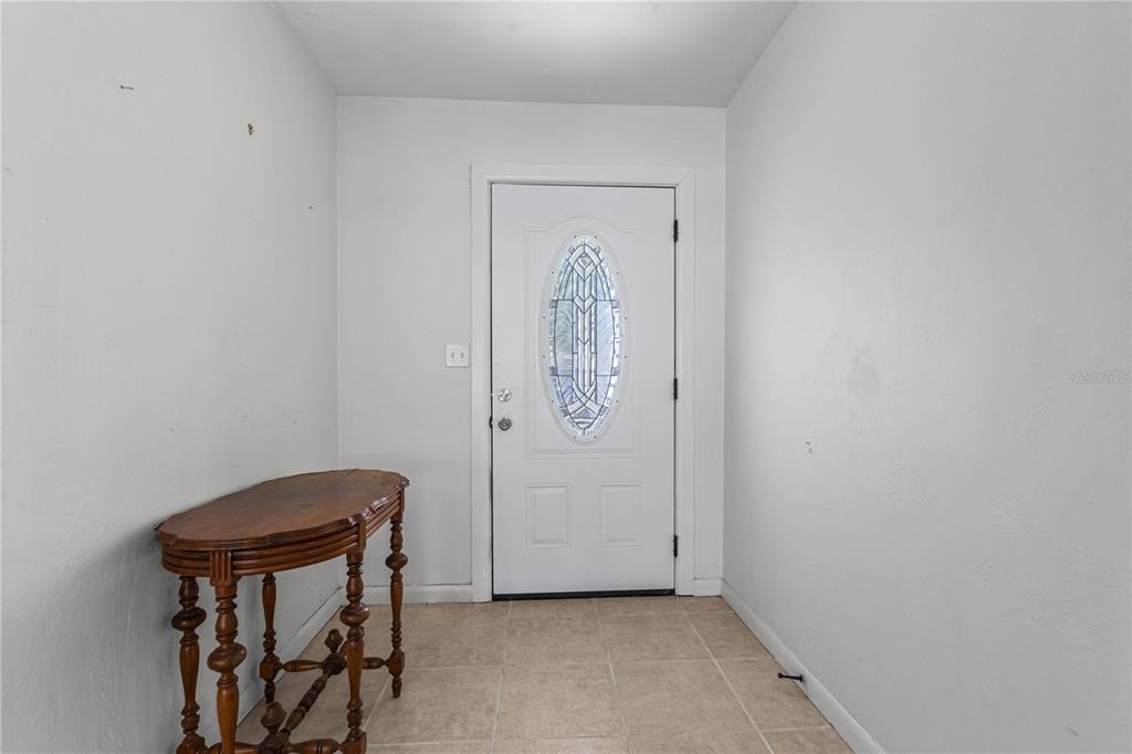 An entryway features a white front door with a decorative glass insert and tile flooring — 11801 NW 72ND TERRACE, ALACHUA, FL