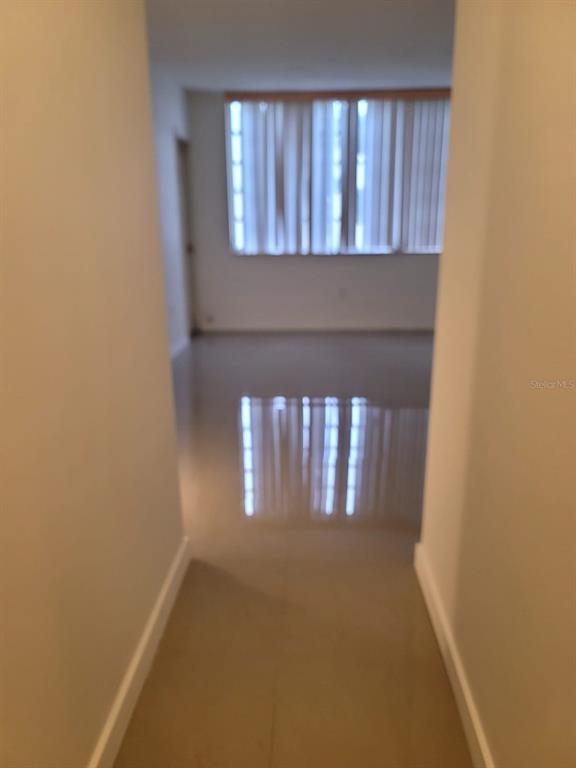 A view through a hallway looking into a room with light-colored tile floors and blinds — 1690 NE 191ST STREET UNIT 315, MIAMI, FL