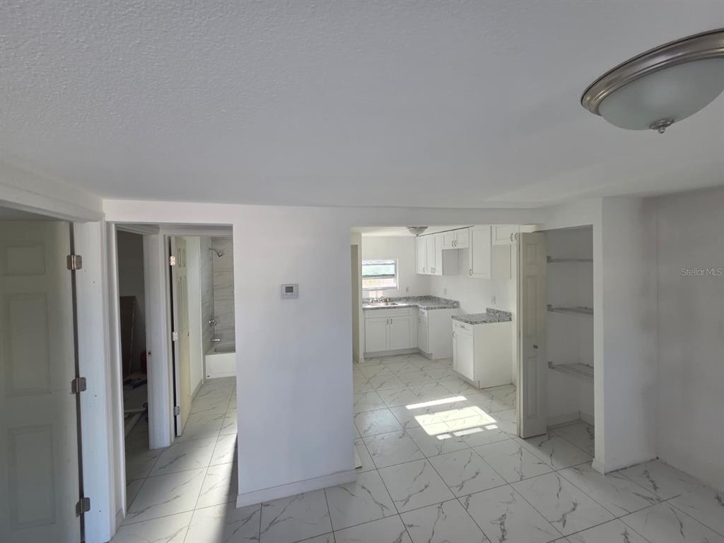 A view of a kitchen and bathroom featuring white cabinets, granite countertops, and tiled floors — 13113 BARTOW STREET, HUDSON, FL