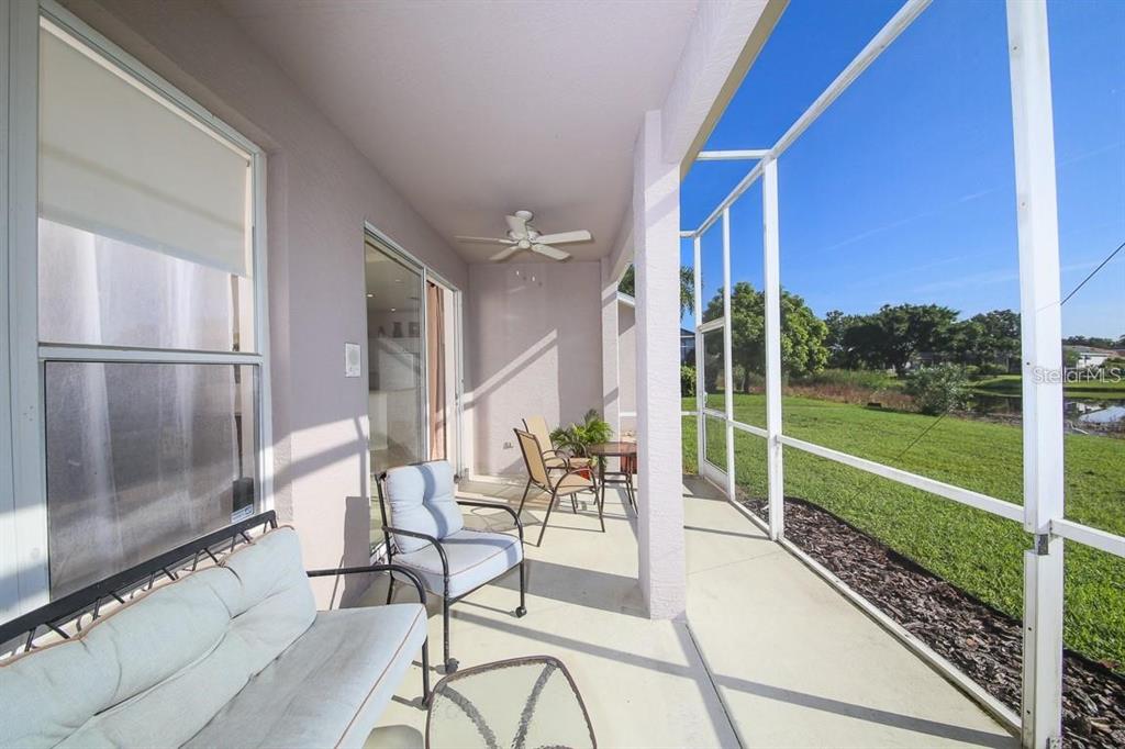 A screened-in patio features a ceiling fan, outdoor furniture, and a view of the lawn — 5041 47TH STREET W, BRADENTON, FL