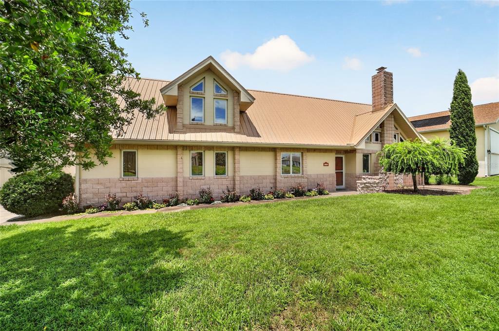 A two-story house with a metal roof, stone siding, and a front-facing dormer window — 9726 SE 70TH TERRACE, OCALA, FL