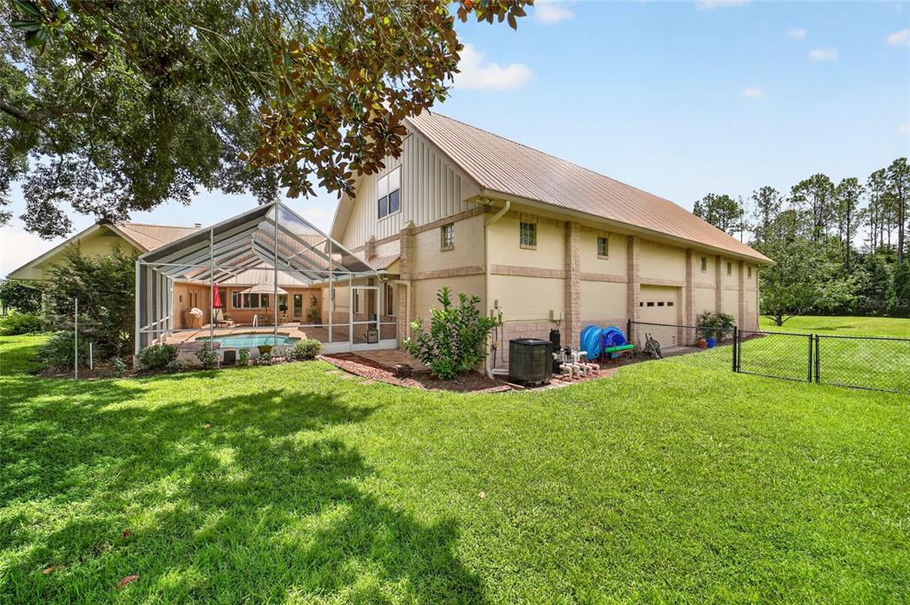 A large house with a metal roof, a screened-in pool, and a fenced backyard — 9726 SE 70TH TERRACE, OCALA, FL