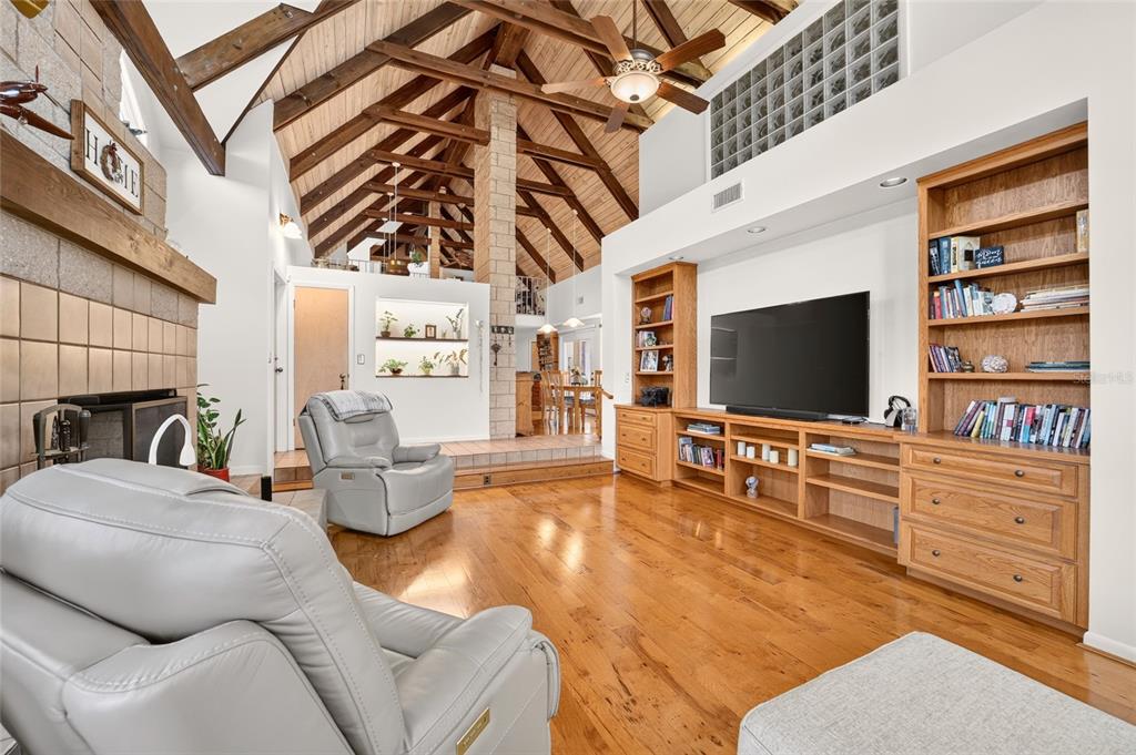 A living room features vaulted wood-beam ceilings, hardwood floors, a stone fireplace, and built-in shelving — 9726 SE 70TH TERRACE, OCALA, FL