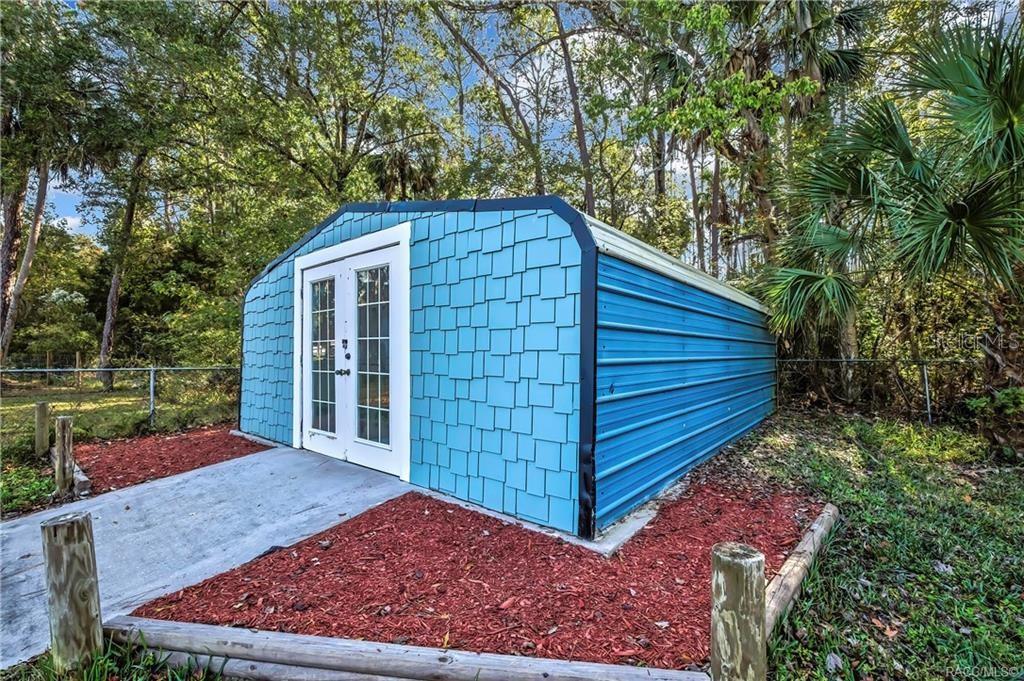 A blue shed with a shingled front and metal sides sits on a concrete pad — 8340 W AMELIA COURT, HOMOSASSA, FL