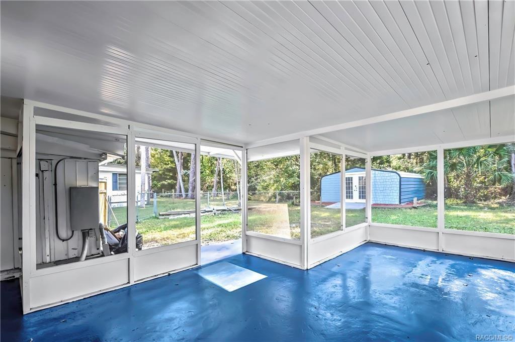 A screened-in porch with a blue painted floor and a view of a backyard shed — 8340 W AMELIA COURT, HOMOSASSA, FL