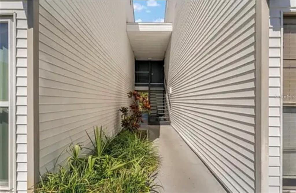 A narrow outdoor walkway leads to a set of stairs and a dark entry door — 654 HAVEN PLACE UNIT 654, TARPON SPRINGS, FL