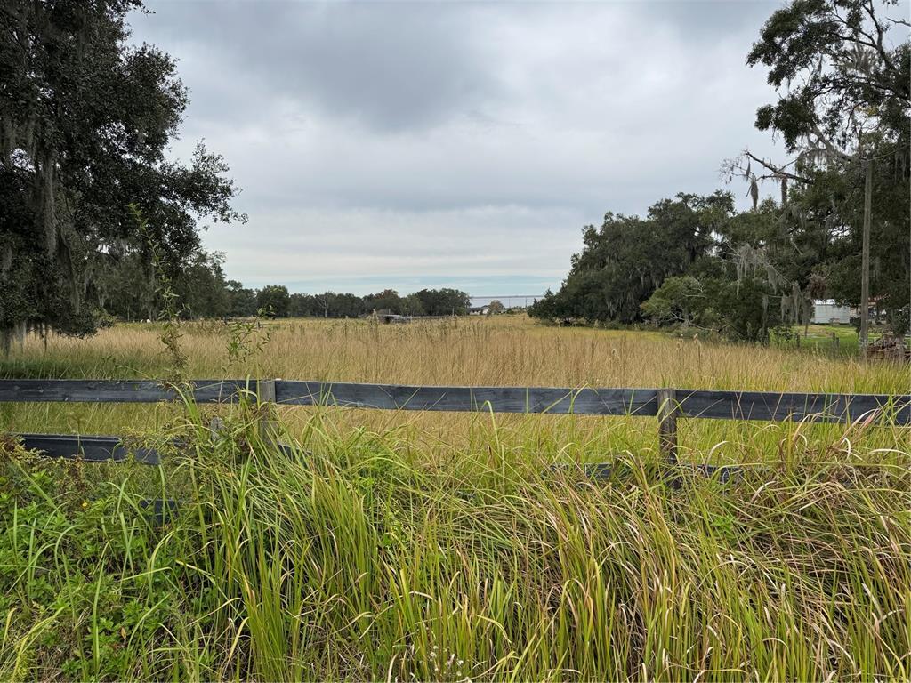 A wooden fence borders a large, grassy field surrounded by trees under a cloudy sky — 0 CASON ROAD, PLANT CITY, FL