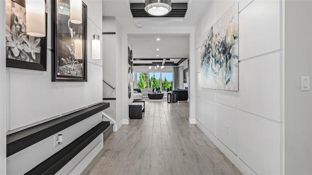 A bright entryway features white paneled walls, wood-look tile flooring, and a view into the living room — 1729 POINT GRACE ROAD, TAVARES, FL