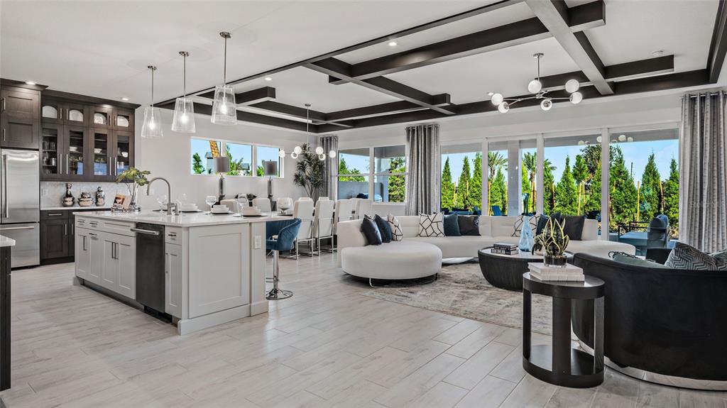An open-concept kitchen and living area features a coffered ceiling, white cabinetry, and large windows — 1729 POINT GRACE ROAD, TAVARES, FL