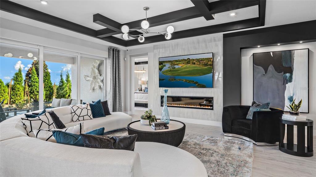 A modern living room features a curved white sofa, a fireplace, and a coffered ceiling — 1729 POINT GRACE ROAD, TAVARES, FL