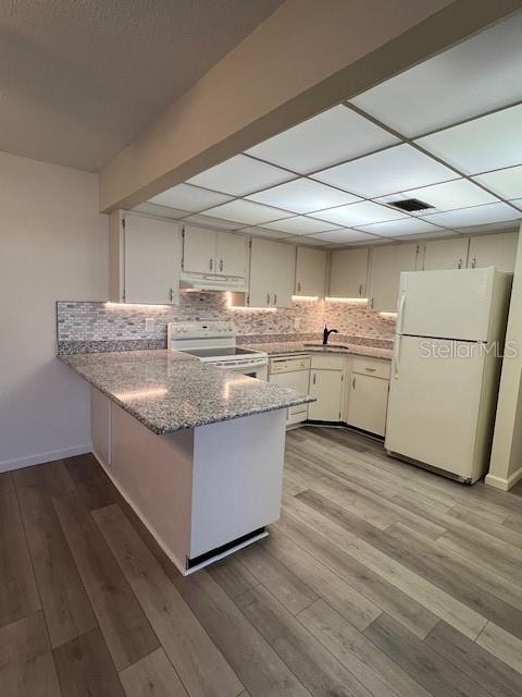A kitchen features white cabinets, granite countertops, a tiled backsplash, and light wood-look flooring — 21260 BRINSON AVENUE UNIT 211, PORT CHARLOTTE, FL