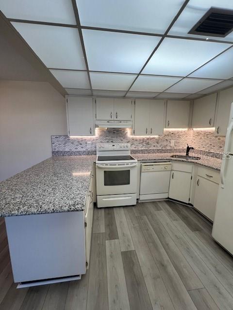 A kitchen features white cabinets, granite countertops, a tiled backsplash, and light wood-look flooring — 21260 BRINSON AVENUE UNIT 211, PORT CHARLOTTE, FL