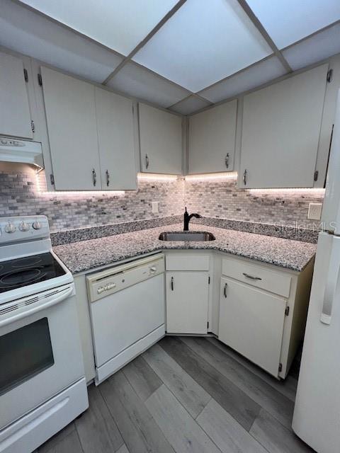 A kitchen features white cabinets, granite countertops, a tiled backsplash, and light wood-look flooring — 21260 BRINSON AVENUE UNIT 211, PORT CHARLOTTE, FL