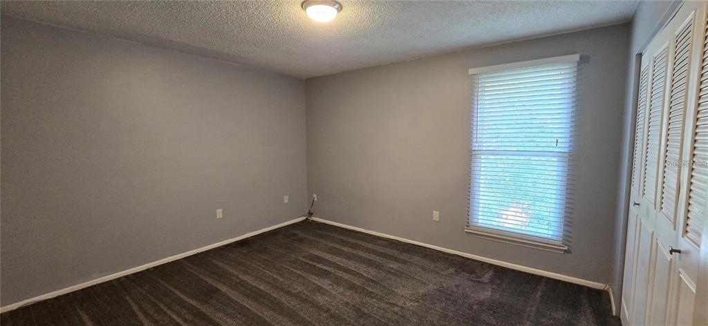 An empty bedroom features gray walls, dark carpeting, a window with blinds, and closet doors — 512 ORANGE DRIVE UNIT 30, ALTAMONTE SPRINGS, FL