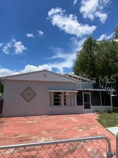 A single-story house with a screened porch and a red paved driveway under a blue sky — 312 MILAKEE AVENUE, SEBRING, FL