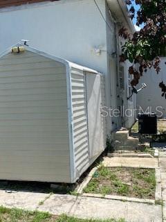 A beige metal storage shed stands on a concrete patio next to a white building — 312 MILAKEE AVENUE, SEBRING, FL