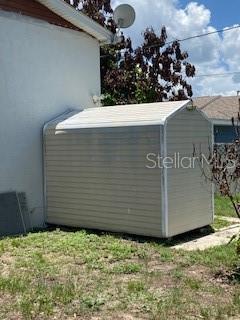 A beige, rectangular storage shed sits on a concrete pad next to a white house — 312 MILAKEE AVENUE, SEBRING, FL