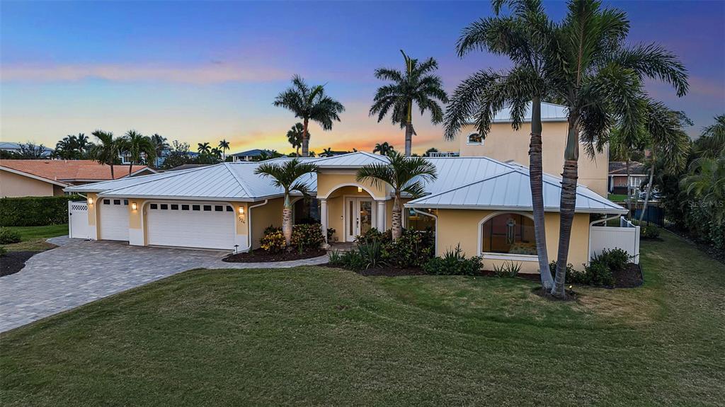 A single-story yellow house with a metal roof and palm trees at dusk — 524 HORNBLOWER LANE, LONGBOAT KEY, FL