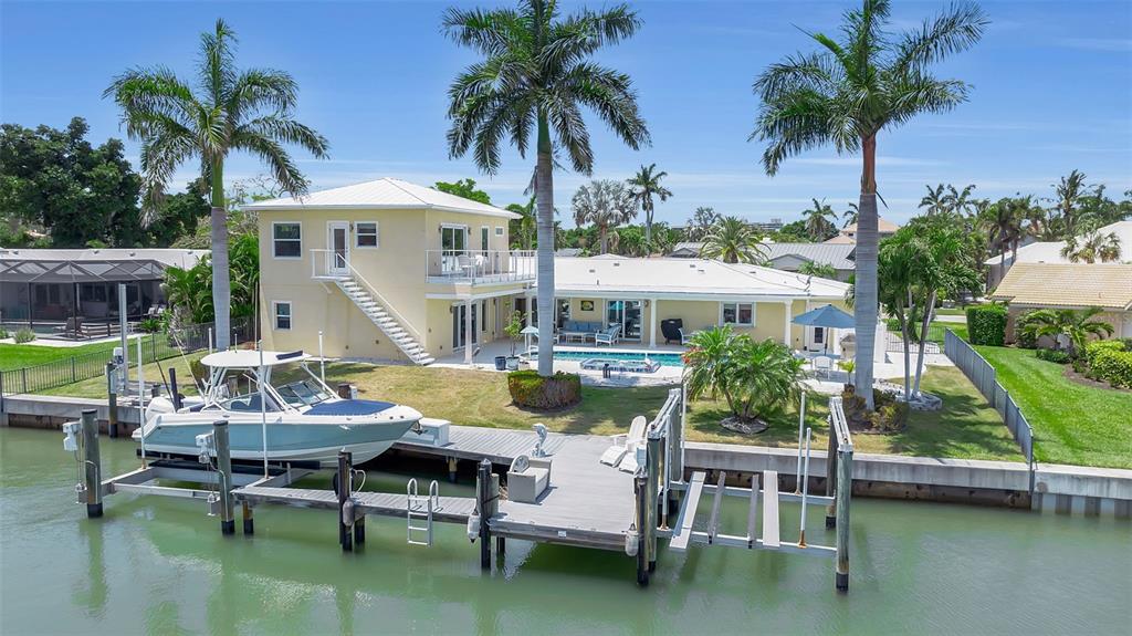 A two-story yellow house with a boat docked at a private pier on the water — 524 HORNBLOWER LANE, LONGBOAT KEY, FL