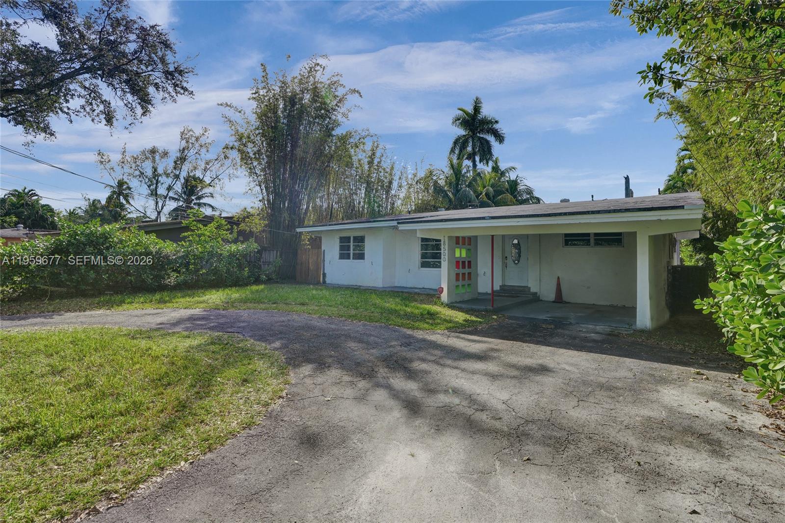 A single-story house with a white exterior, a carport, and a curved asphalt driveway — 18500 NE 23rd Ct, Miami FL 33180, MIAMI, FL
