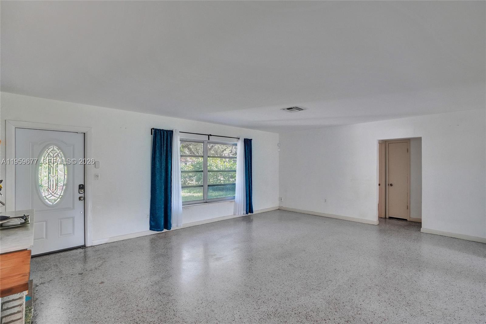 An empty room with white walls, a terrazzo floor, and a front door with glass — 18500 NE 23rd Ct, Miami FL 33180, MIAMI, FL