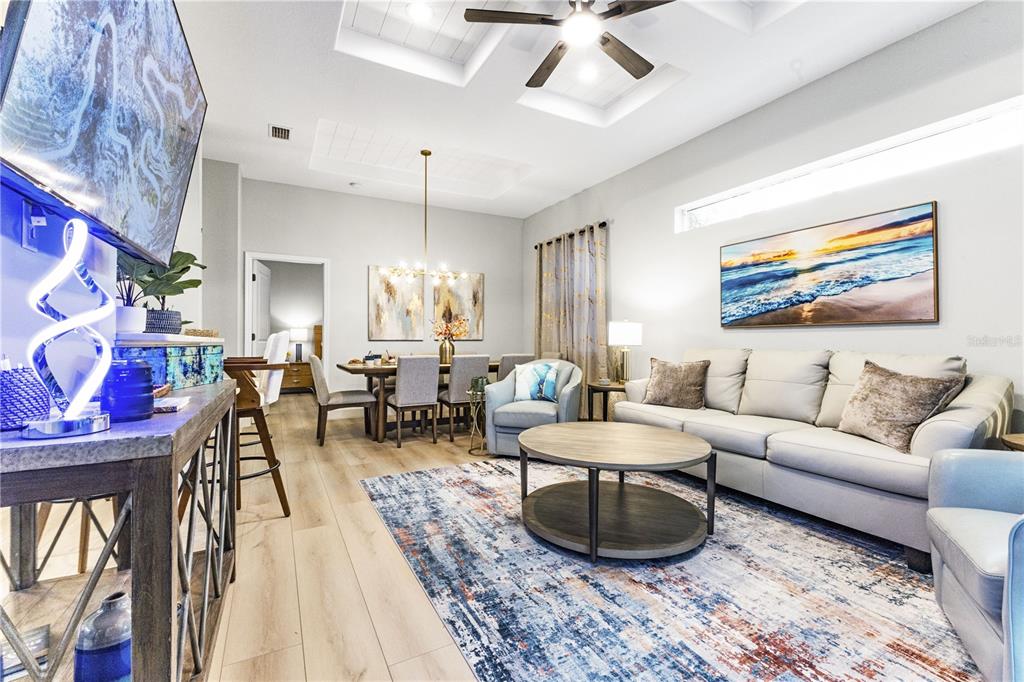 A living room and dining area feature light wood flooring, a ceiling fan, and furniture — 2047 ROSELAWN STREET, SARASOTA, FL