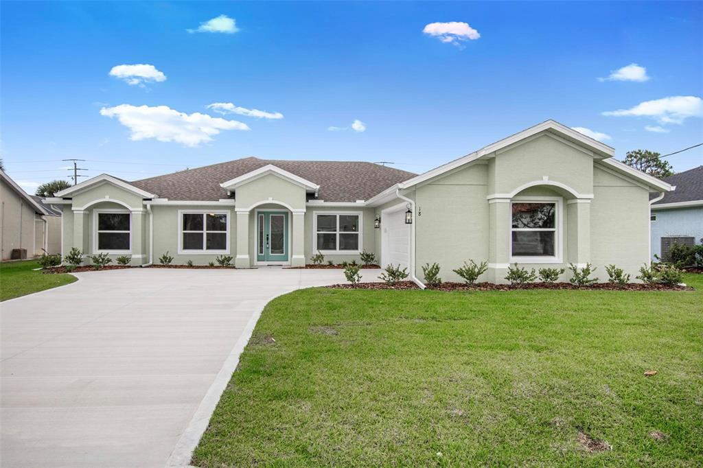 A light green single-story house features a concrete driveway, a front porch, and landscaping — 18 CENTRAL PLACE, PALM COAST, FL