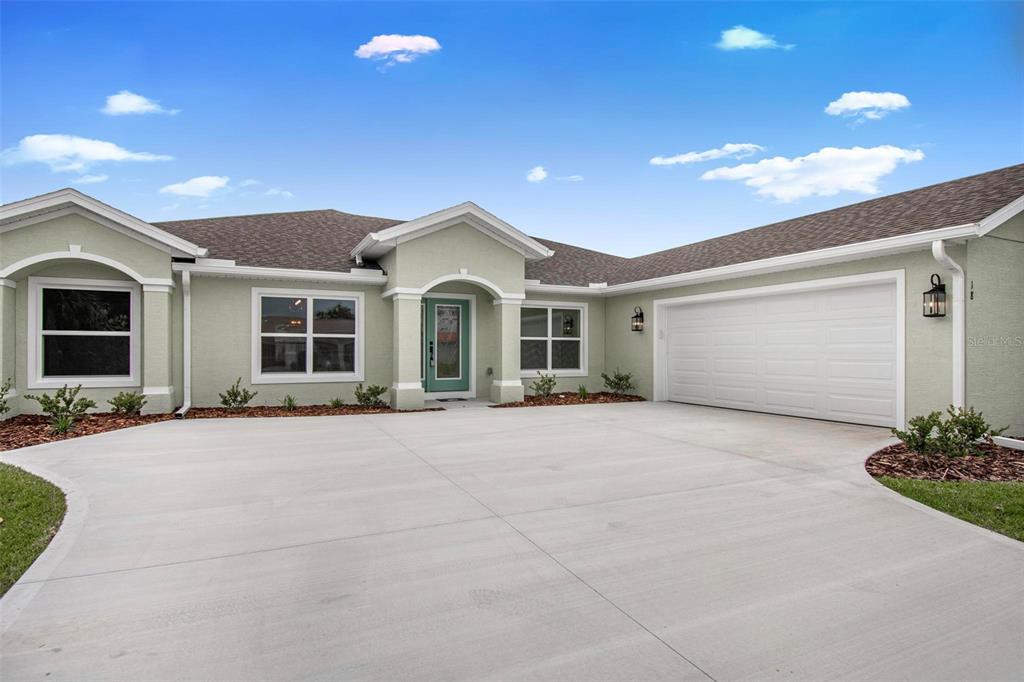 A light green single-story house with a two-car garage and a concrete driveway — 18 CENTRAL PLACE, PALM COAST, FL