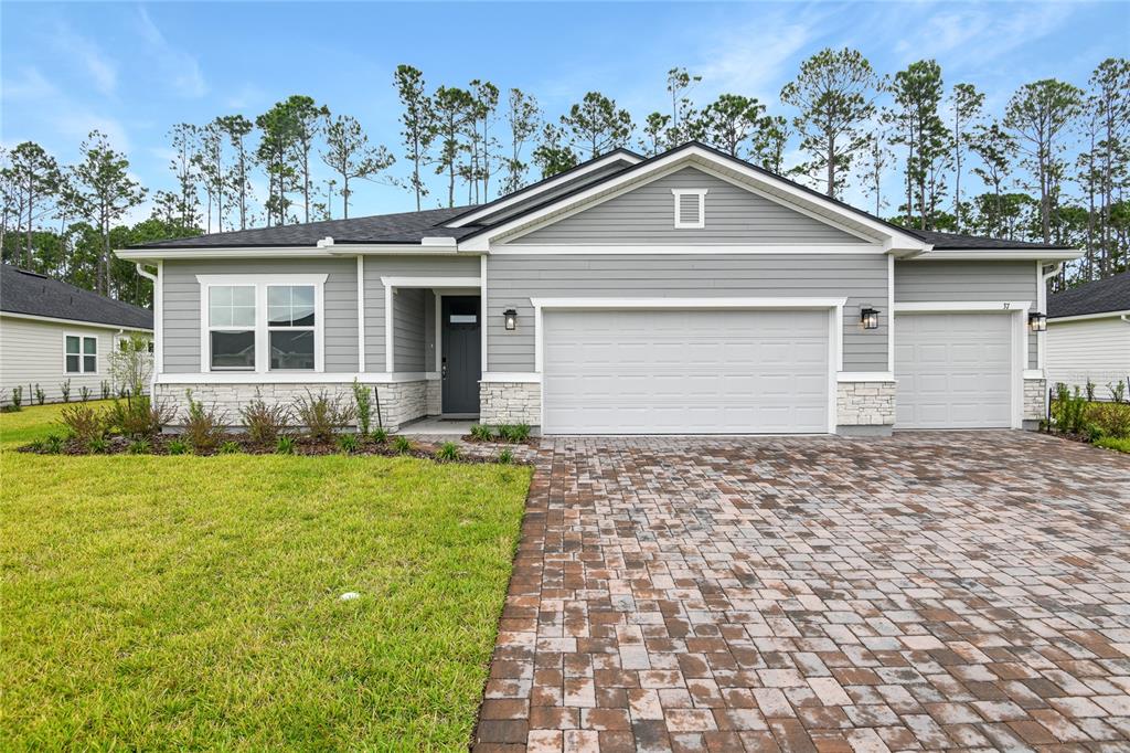 A single-story house with gray horizontal siding, stone accents, and a paved driveway — 37 PONCE PRESERVE DRIVE, PALM COAST, FL