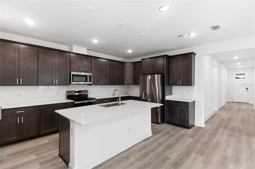 A kitchen with dark wood cabinets, white countertops, a central island, and light wood flooring — 37 PONCE PRESERVE DRIVE, PALM COAST, FL