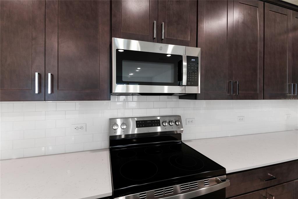 A kitchen features dark wood cabinets, a stainless steel microwave, and a black electric range — 37 PONCE PRESERVE DRIVE, PALM COAST, FL