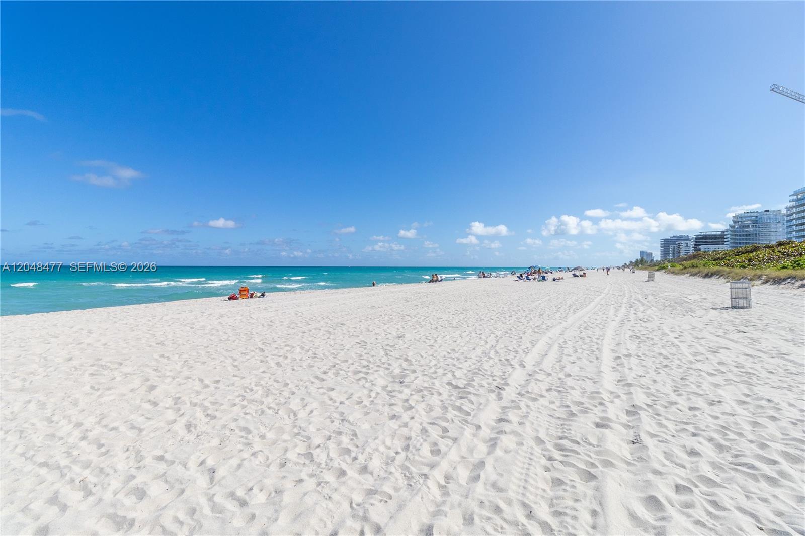 A wide, sandy beach stretches toward the ocean under a clear blue sky — 7860 Harding Ave # 4B, Miami Beach FL 33141, MIAMI BEACH, FL