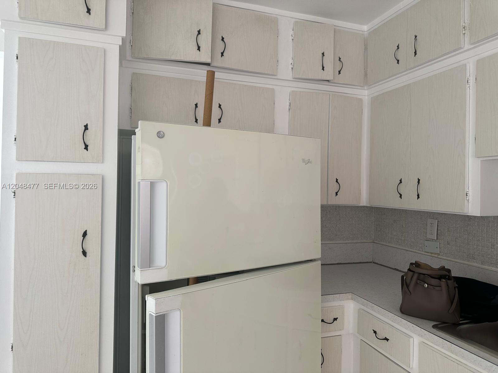 A kitchen features light-colored wood-grain cabinets, a white refrigerator, and a grey countertop — 7860 Harding Ave # 4B, Miami Beach FL 33141, MIAMI BEACH, FL