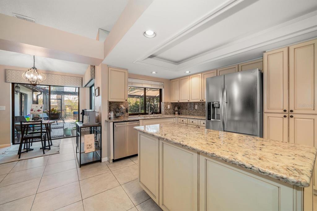 A kitchen with cream cabinets, granite countertops, stainless steel appliances, and an adjacent dining area — 3408 FAIRFIELD TRAIL, CLEARWATER, FL