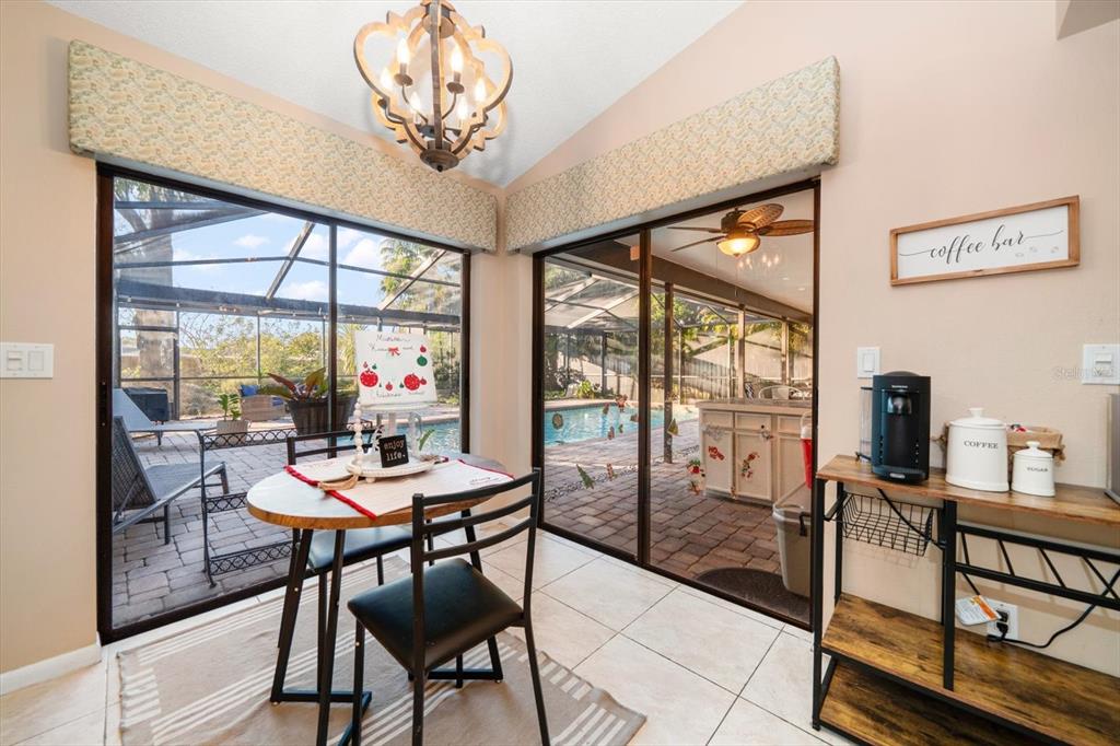 A dining area features a small table, a coffee station, and sliding glass doors to a pool — 3408 FAIRFIELD TRAIL, CLEARWATER, FL