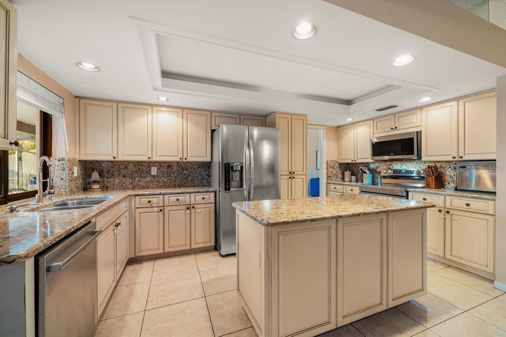 A kitchen with cream cabinets, granite countertops, a center island, and stainless steel appliances — 3408 FAIRFIELD TRAIL, CLEARWATER, FL