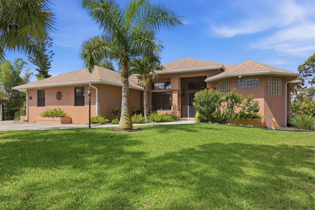 A single-story stucco house with a hip roof, palm trees, and a front lawn — 1710 PARKER DRIVE, ENGLEWOOD, FL