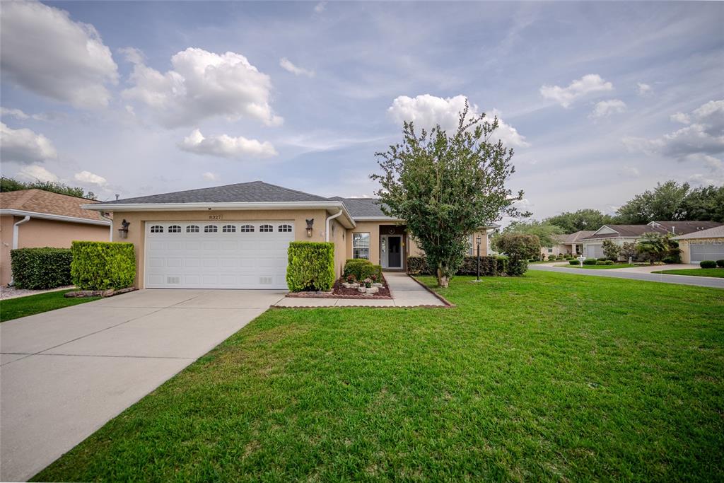 A single-story house with a white garage door, tan stucco exterior, and a front lawn — 8327 SW 79TH CIRCLE, OCALA, FL