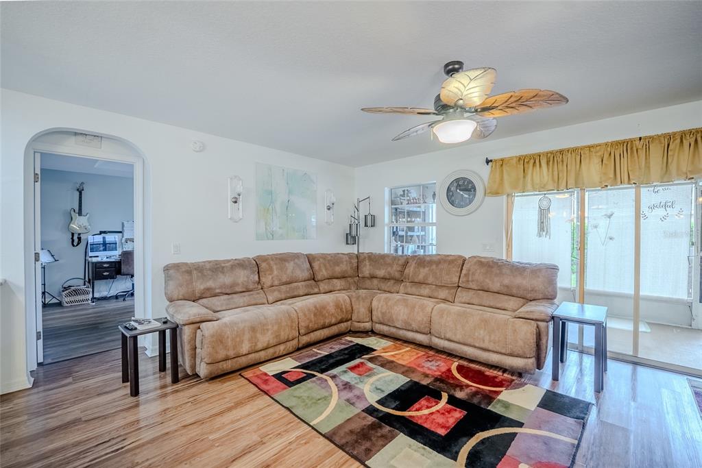 A living room features a large sectional sofa, a colorful area rug, and a ceiling fan — 8327 SW 79TH CIRCLE, OCALA, FL