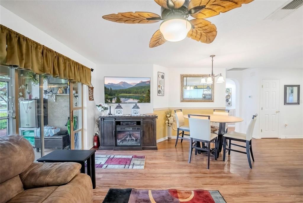 A living and dining area features wood-look flooring, a ceiling fan, and a fireplace console — 8327 SW 79TH CIRCLE, OCALA, FL