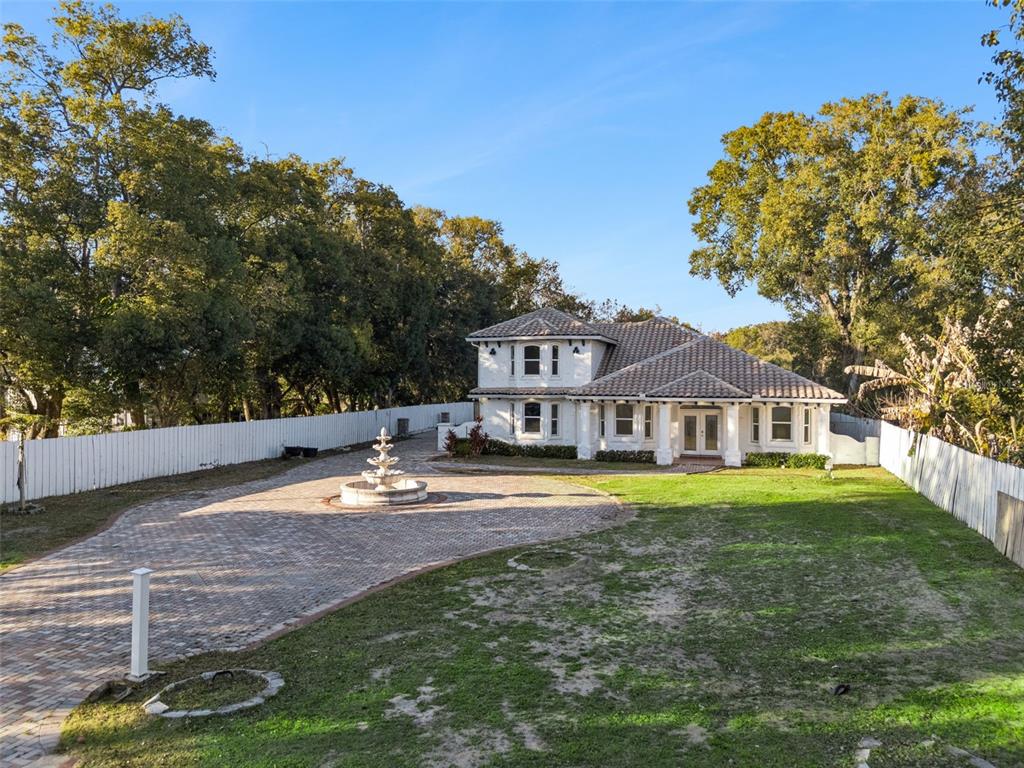 A two-story white house with a tiled roof features a circular brick driveway and fountain — 20 REWIS STREET, OCOEE, FL