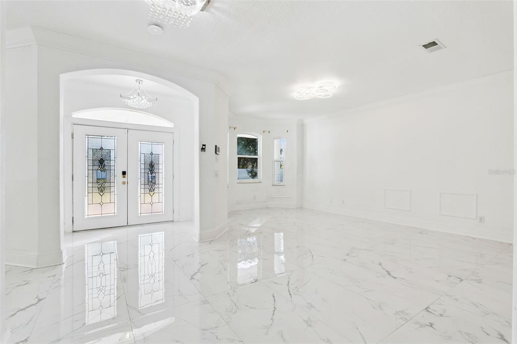 An empty room with white marble floors, a double front door, and modern ceiling lights — 20 REWIS STREET, OCOEE, FL
